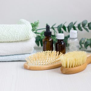 Composition with hair care products, towel and brush on wooden table.