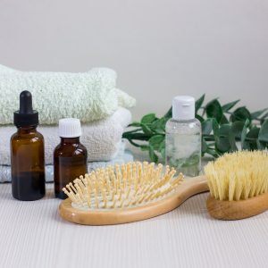 Composition with hair care products, towel and brush on wooden table
