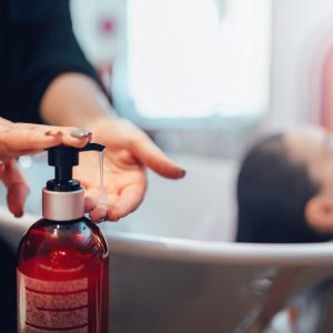 Hairdresser washes customer hair with shampoo