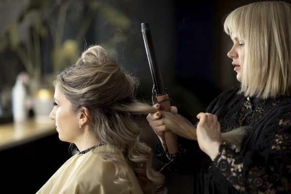 Makeup artist doing hair styling on a curling iron