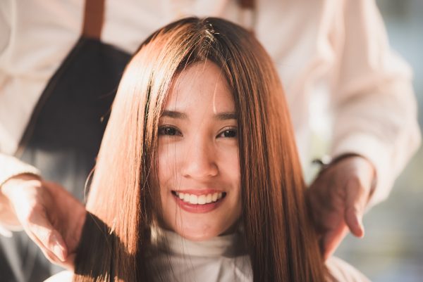 Professional hirdresser design the hair style of smilling young lady with bright brown
